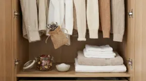 Interno di un armadio con abiti ordinati, sacchetto profumato e asciugamani piegati
