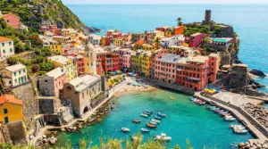 Colorato borgo sul mare con barche ormeggiate e case affacciate sull'acqua in una giornata di sole