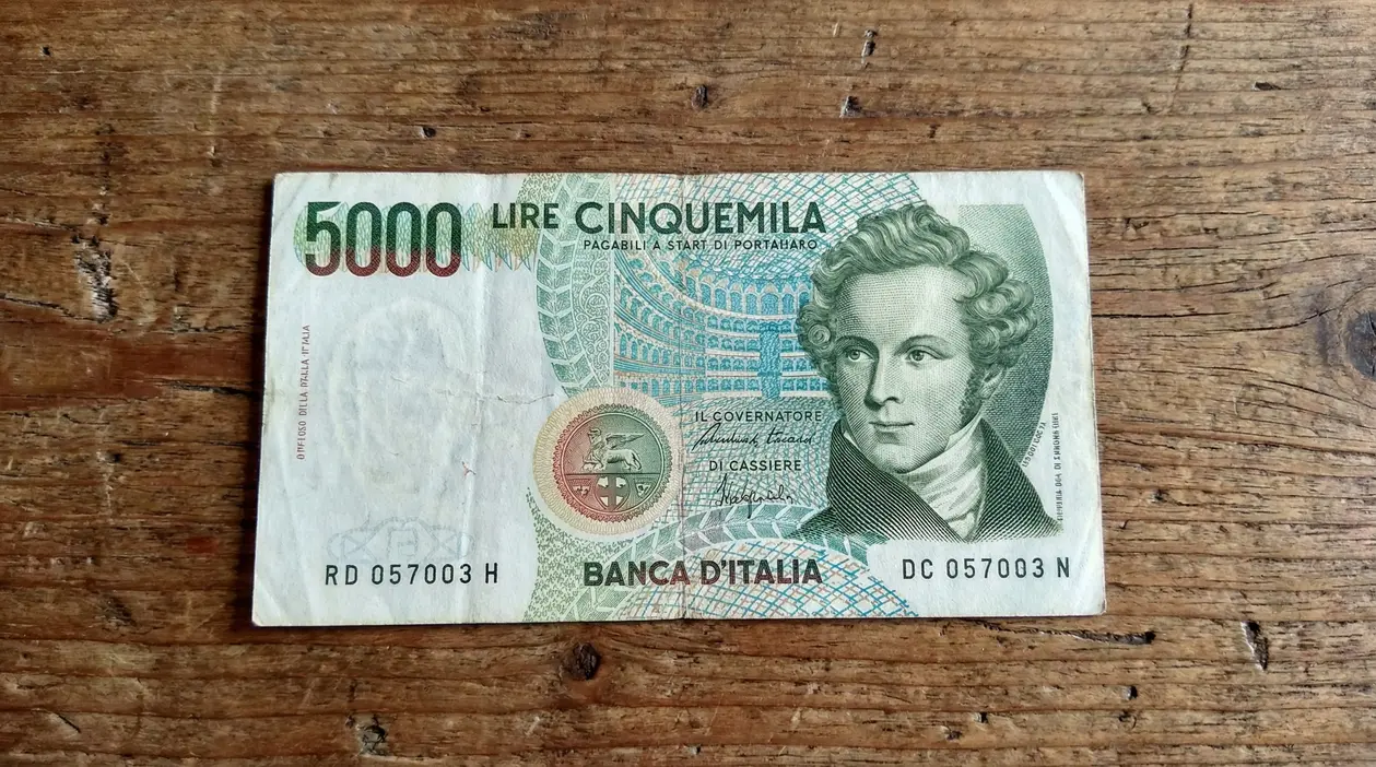 Banconota italiana da 5.000 lire su tavolo in legno